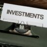 a close up of a typewriter with a paper that reads investments